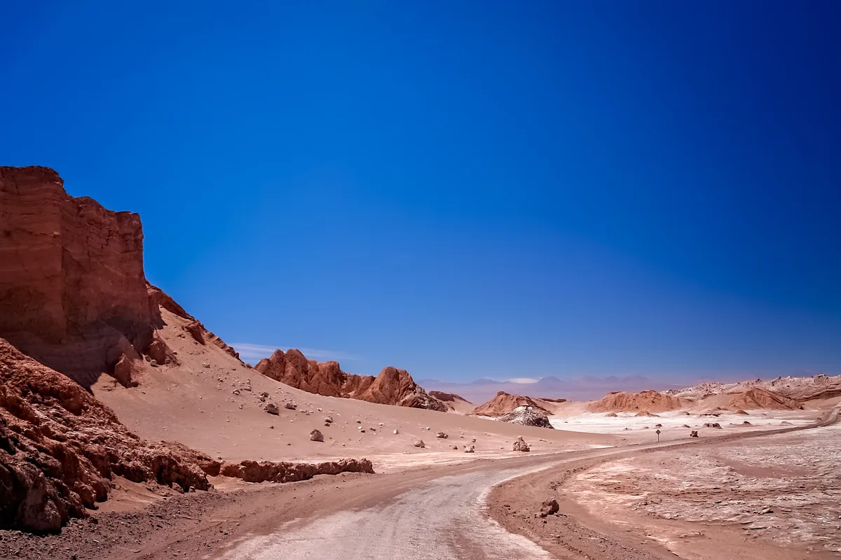 Road through Moon Valley in Atacama Desert at sunset, showing the prepared vehicle journey through otherworldly landscape